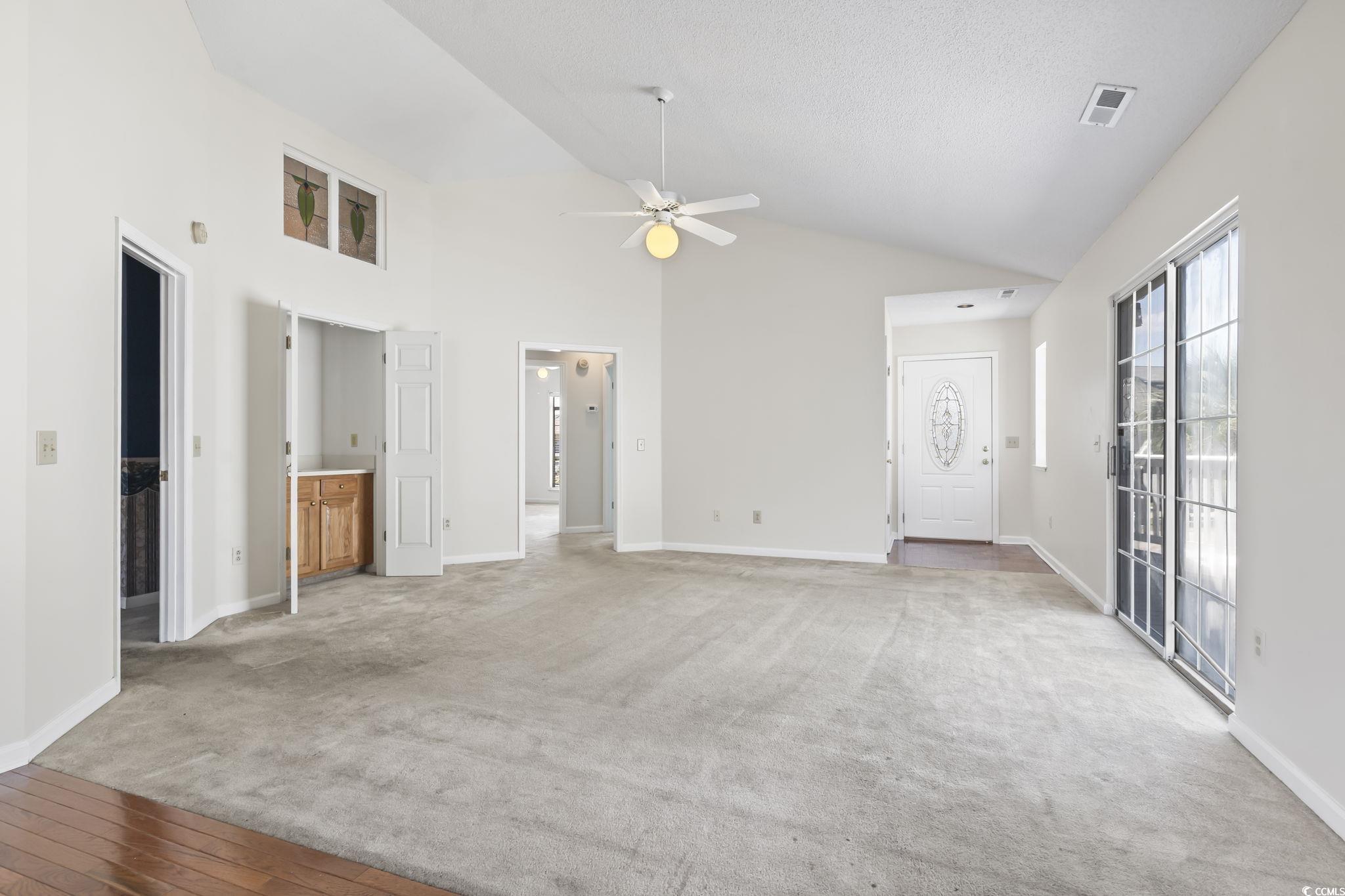914 Dock Place Murrells Inlet, SC 29576 - Photo 14 of 37 Unfurnished living room with ceiling fan, baseboards, light carpet, and high vaulted ceiling