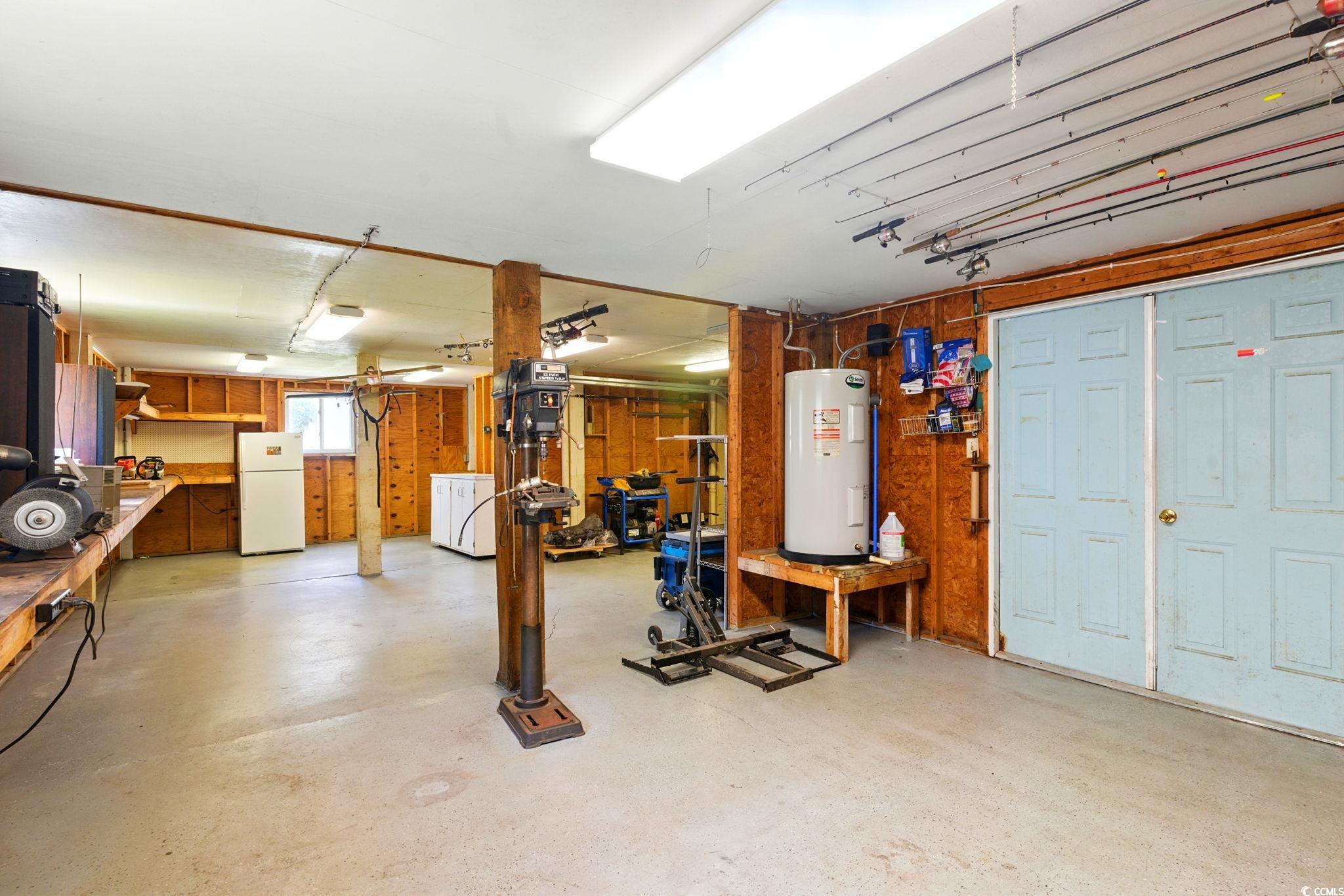 914 Dock Place Murrells Inlet, SC 29576 - Photo 33 of 37 Basement featuring electric water heater, freestanding refrigerator, washer / clothes dryer, and a workshop area