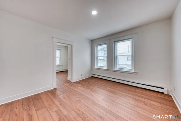 an empty room with wooden floor and windows