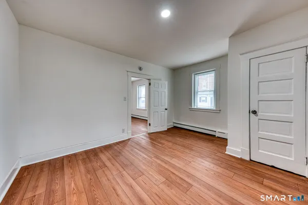 an empty room with wooden floor closet and windows