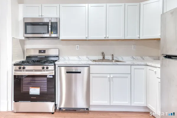 a kitchen with granite countertop a stove top oven microwave and cabinets