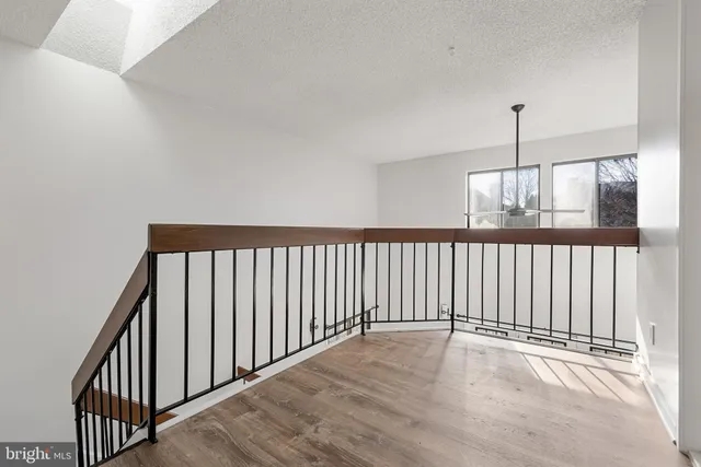 a view of a hallway with wooden floor and chandelier