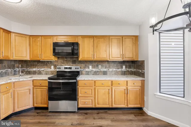 a kitchen with granite countertop a stove a sink and a microwave