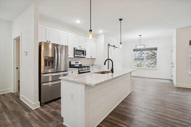 a kitchen with stainless steel appliances a refrigerator and a hard wood floor