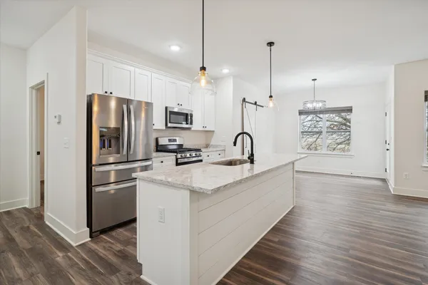a kitchen with stainless steel appliances a refrigerator and a hard wood floor