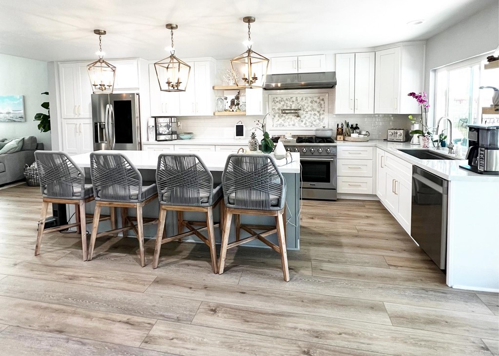 3583 Hatfield Circle Oceanside, CA 92056 - Photo 10 of 32 a kitchen with stainless steel appliances granite countertop a stove top oven a sink dishwasher and a dining table with wooden floor