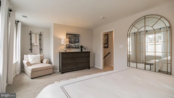 a spacious bedroom with a bed a couch and large window