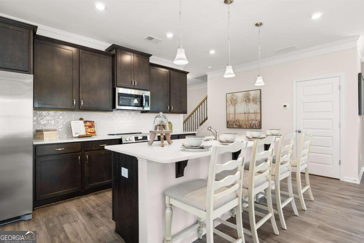 1429 Trellis Court, Unit (LOT 9) Hampton, GA 30228 - Photo 6 of 28 a kitchen with stainless steel appliances kitchen island granite countertop a sink and cabinets