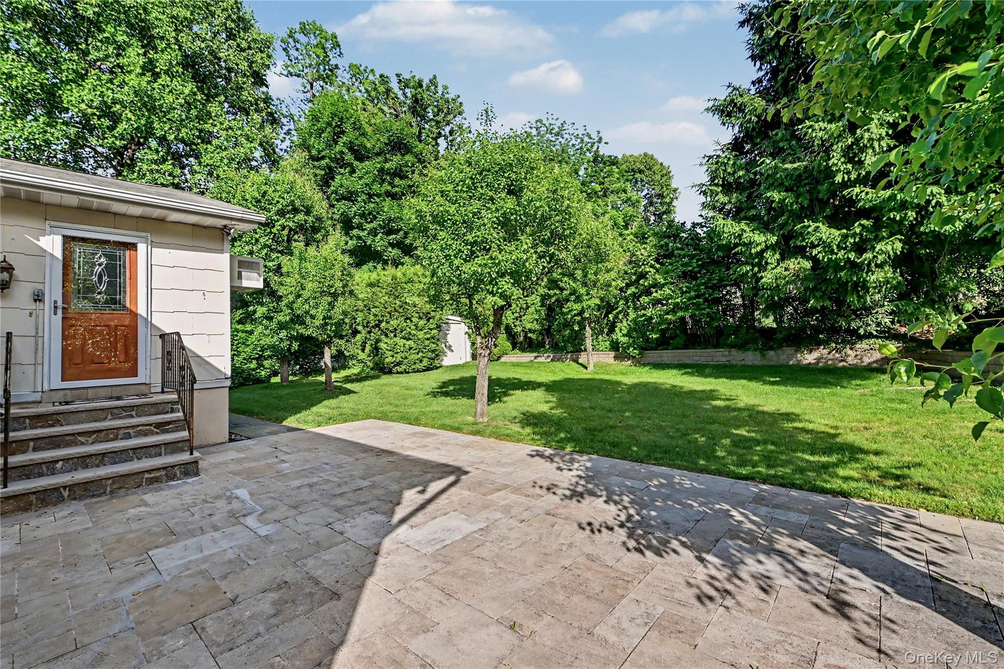568 Manville Road, Unit UPPER R Pleasantville, NY 10570 - Photo 31 of 32 E Door from the family room leads out to an expansive patio with stone pavers, leading to a sprawling lawn surrounded by mature trees