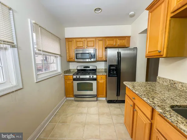 a kitchen with kitchen island granite countertop a stove refrigerator and microwave