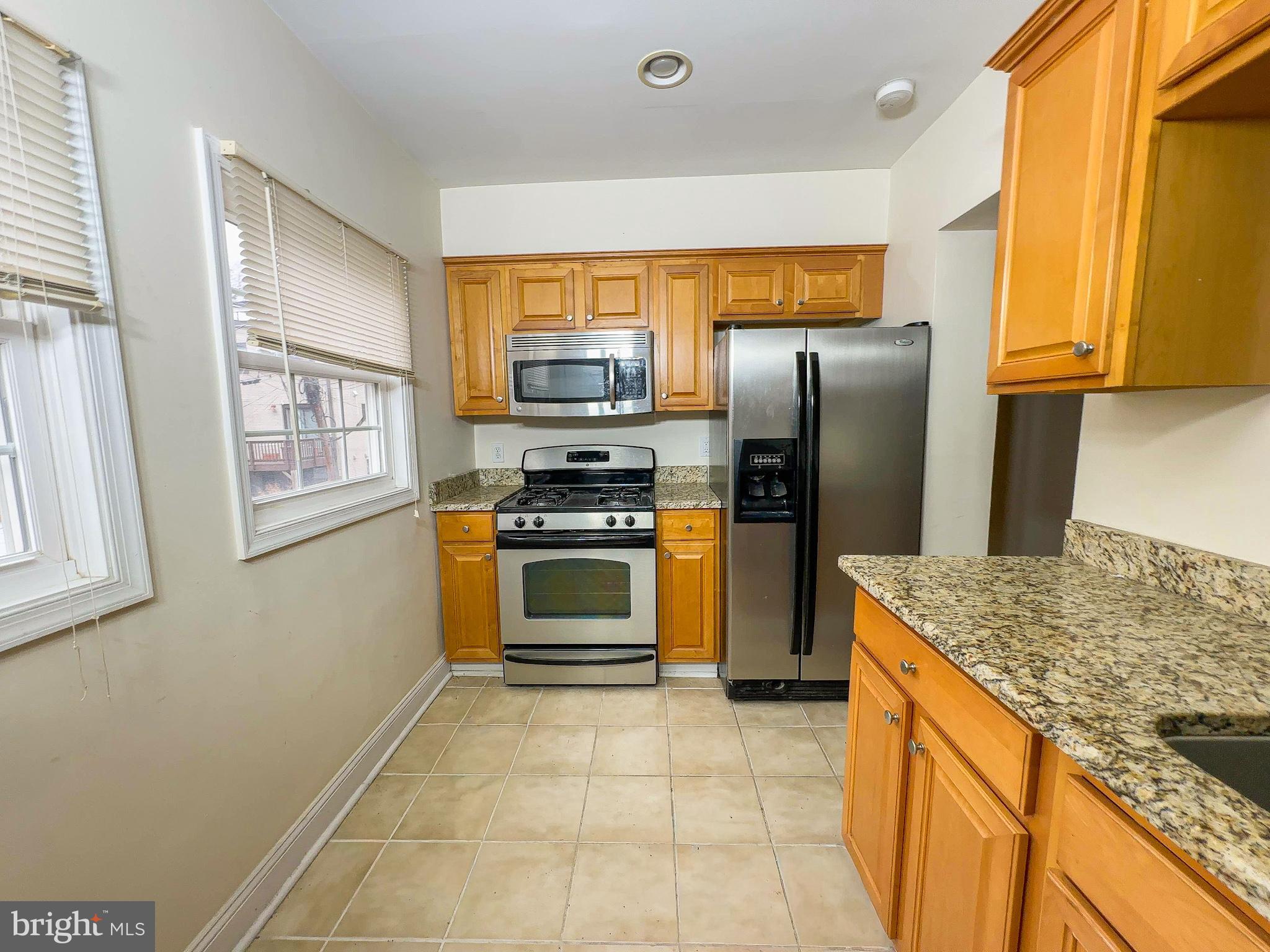 1835 D Street Northeast Washington, DC 20002 - Photo 38 of 42 a kitchen with kitchen island granite countertop a stove refrigerator and microwave
