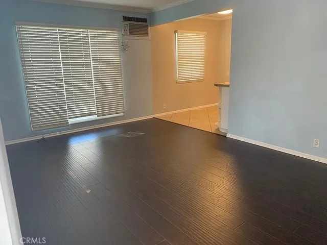 an empty room with wooden floor and windows with curtains