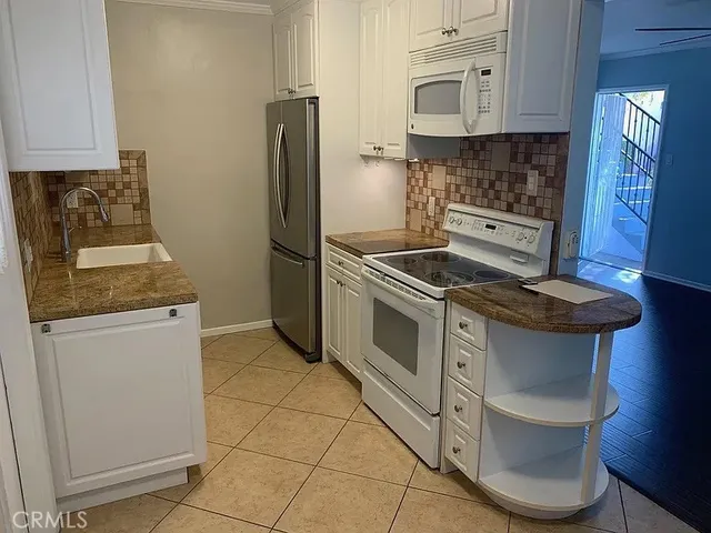 a kitchen with granite countertop a stove microwave and refrigerator