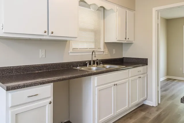 a kitchen with granite countertop white cabinets and a sink