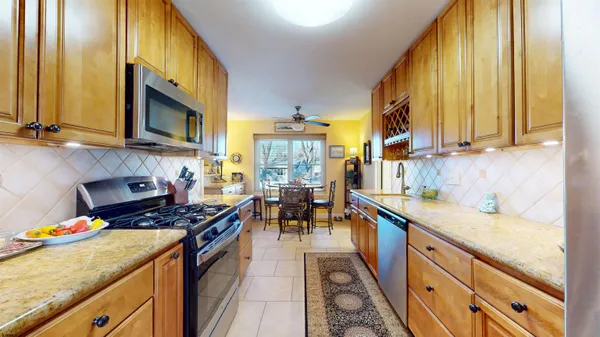 a kitchen with stainless steel appliances granite countertop a sink a stove and a wooden floors