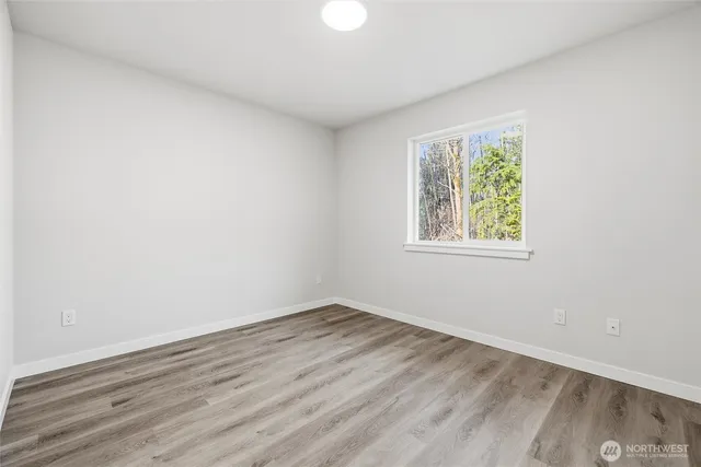 an empty room with wooden floor and window