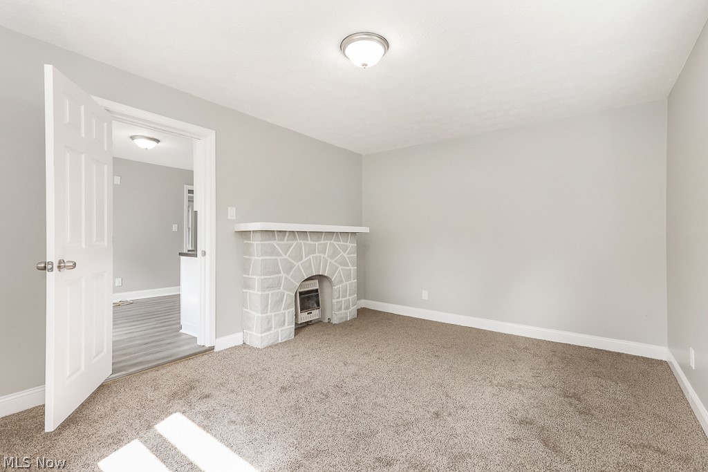 6665 State Road Cleveland, OH 44134 - Photo 17 of 30 Unfurnished living room with a stone fireplace and light colored carpet