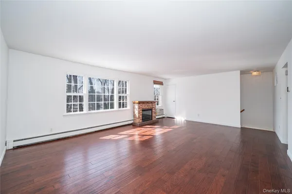 a view of empty room with wooden floor and fireplace
