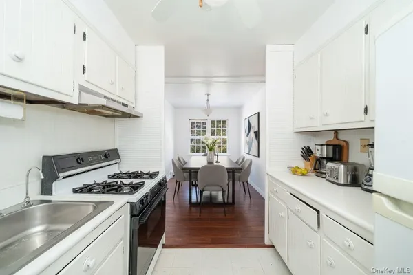 a kitchen with a stove a sink dishwasher and white cabinets with wooden floor