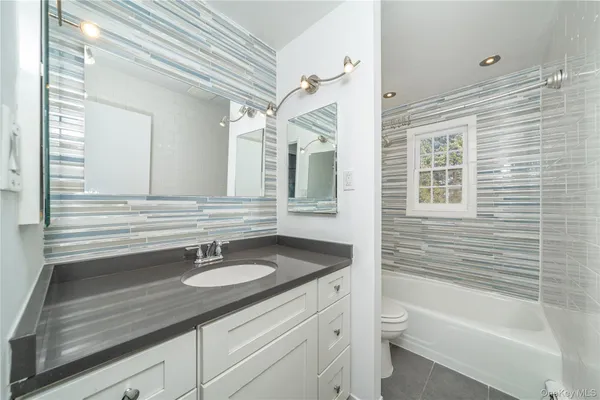 a bathroom with a sink double vanity granite tub and a mirror