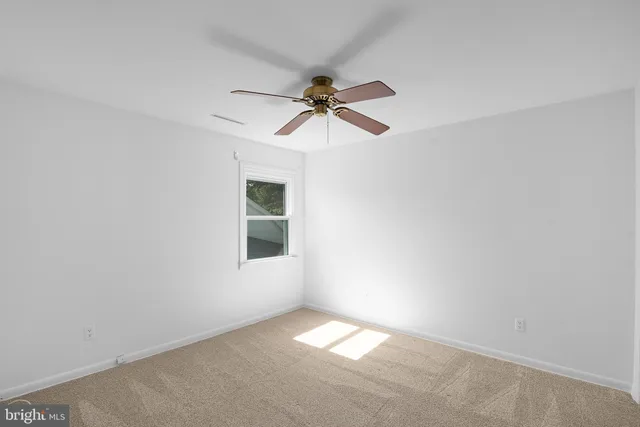 an empty room with a window and a chandelier fan