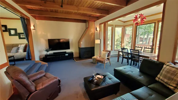 a living room with furniture a flat screen tv and a floor to ceiling window