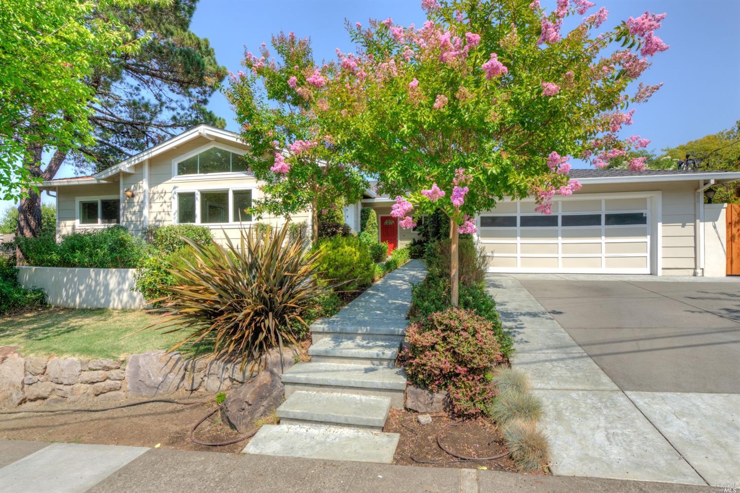 a front view of a house with a yard and potted plants