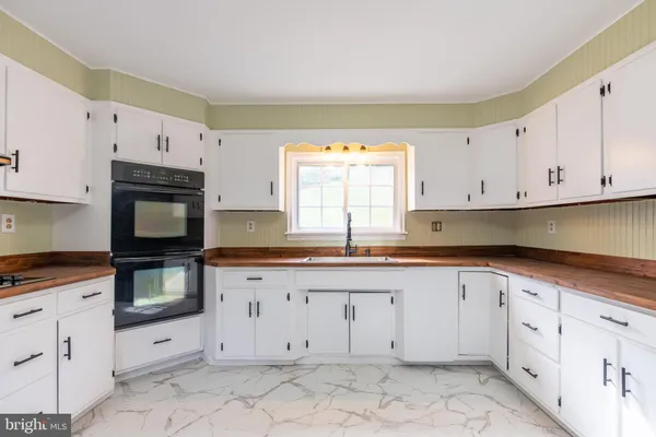 a kitchen with granite countertop white cabinets stainless steel appliances a sink and a window