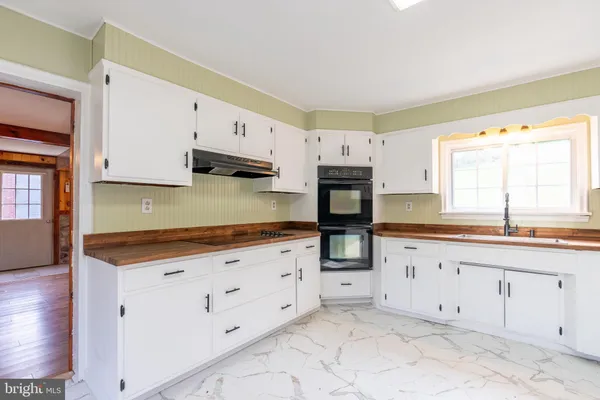a kitchen with granite countertop white cabinets sink and stainless steel appliances