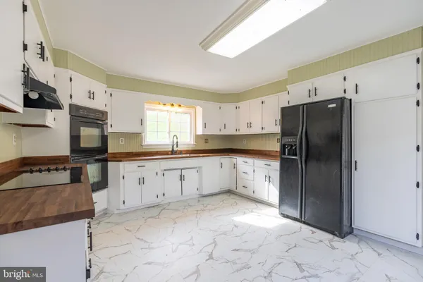 a kitchen with granite countertop a refrigerator and a stove top oven