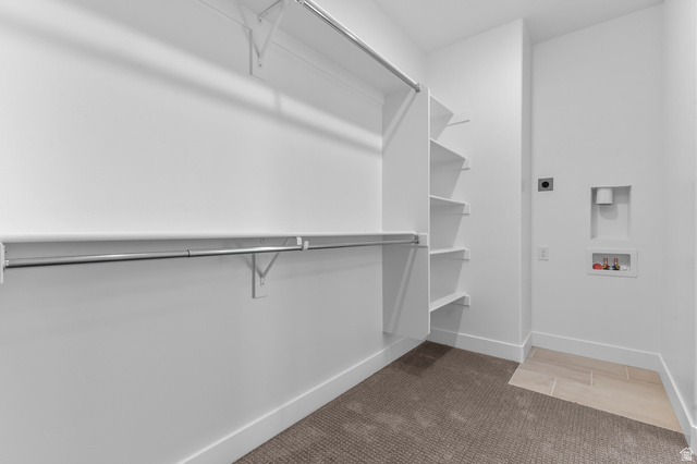 1341 West 2350 South, Unit 10 Perry, UT 84302 - Photo 13 of 18 Walk-in closet featuring extensive built-in shelving and hanging rods, plush carpeting, and an integrated laundry area with tile flooring and utility hookups