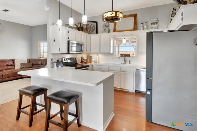 a kitchen with stainless steel appliances a table chairs and a refrigerator