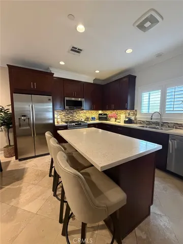 a kitchen with stainless steel appliances granite countertop a table chairs sink refrigerator and microwave
