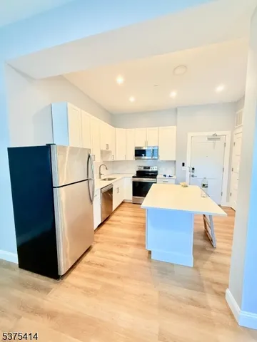 a large white kitchen with cabinets a sink a refrigerator and a stove
