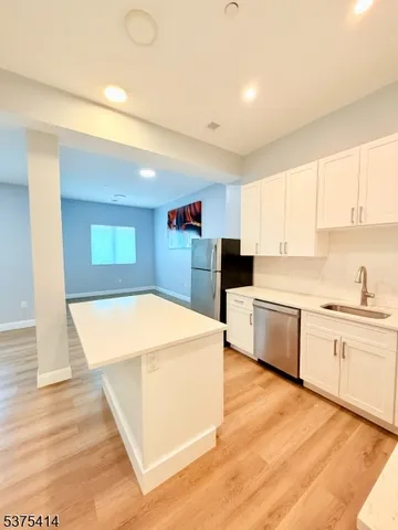 a kitchen with stainless steel appliances kitchen island wooden cabinets a stove a sink and a refrigerator