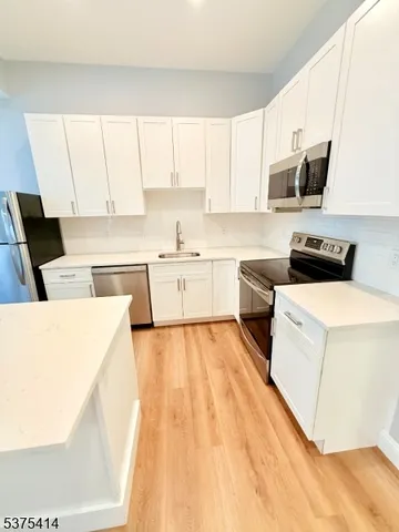 a kitchen with a sink a stove and white cabinets