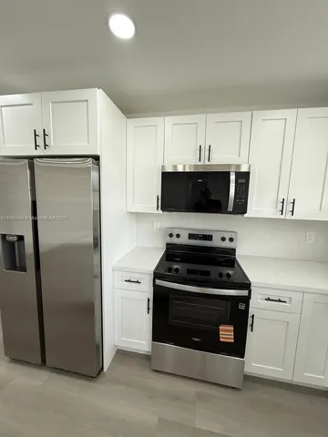 a kitchen with white cabinets and stainless steel appliances