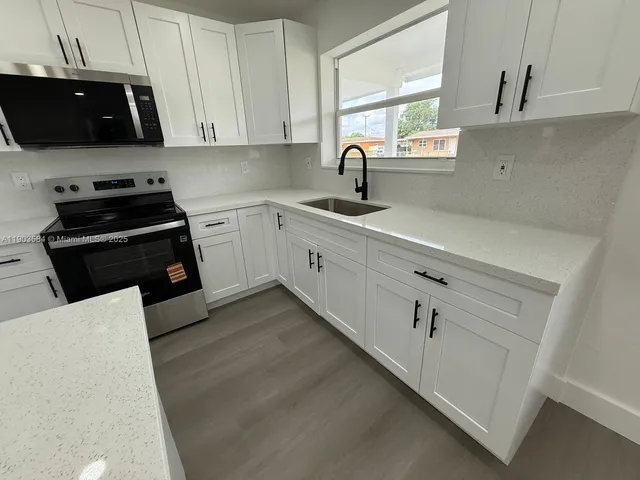 a kitchen with cabinets appliances a sink and a window