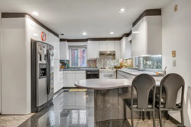 a kitchen with stainless steel appliances granite countertop a refrigerator a sink a stove a dining table and chairs