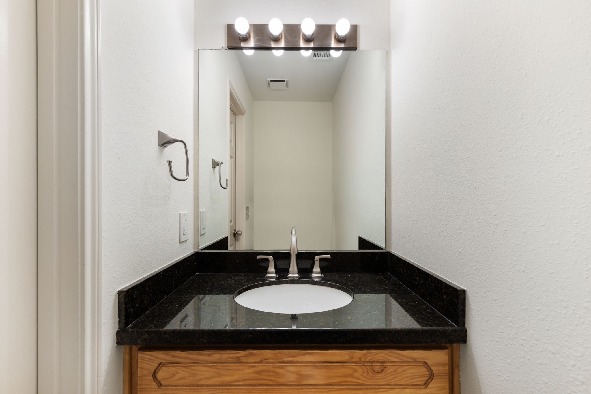 59 Fire Flicker Place Spring, TX 77381 - Photo 17 of 37 Guest bathroom downstairs with a sleek black granite countertop, an undermount sink, and a large mirror