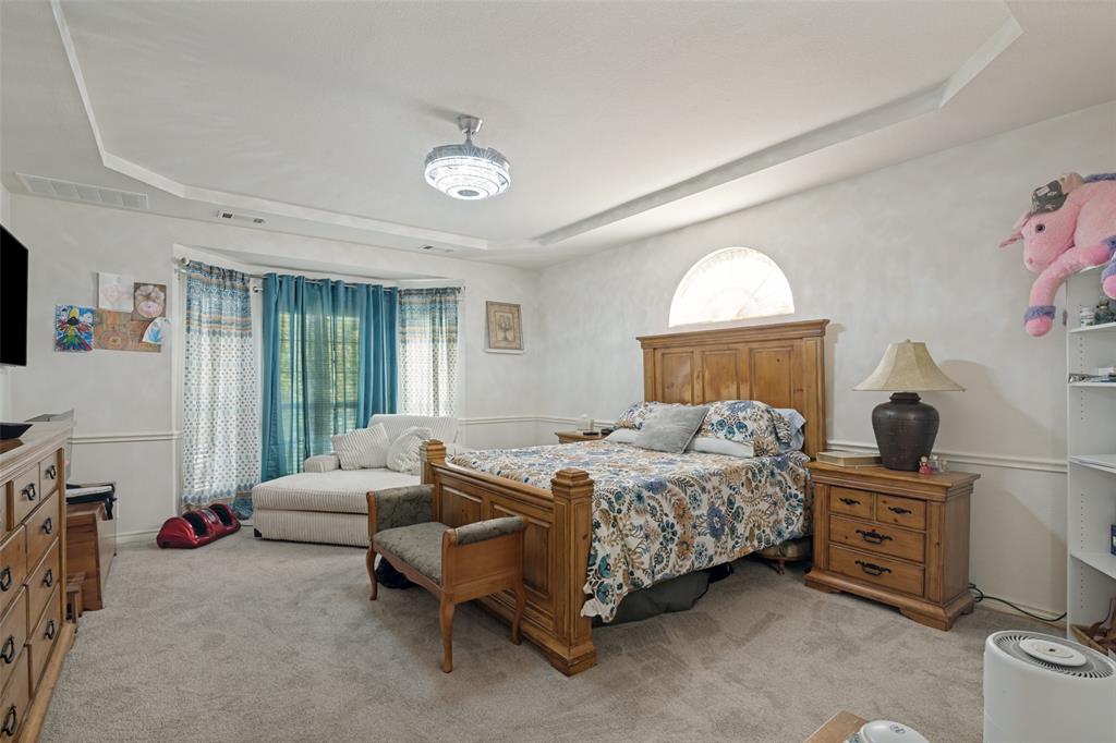 2213 Ranch Road Sachse, TX 75048 - Photo 19 of 28 Tray ceiling with a decorative lighting fixture, arched window, and bay window with layered window treatments