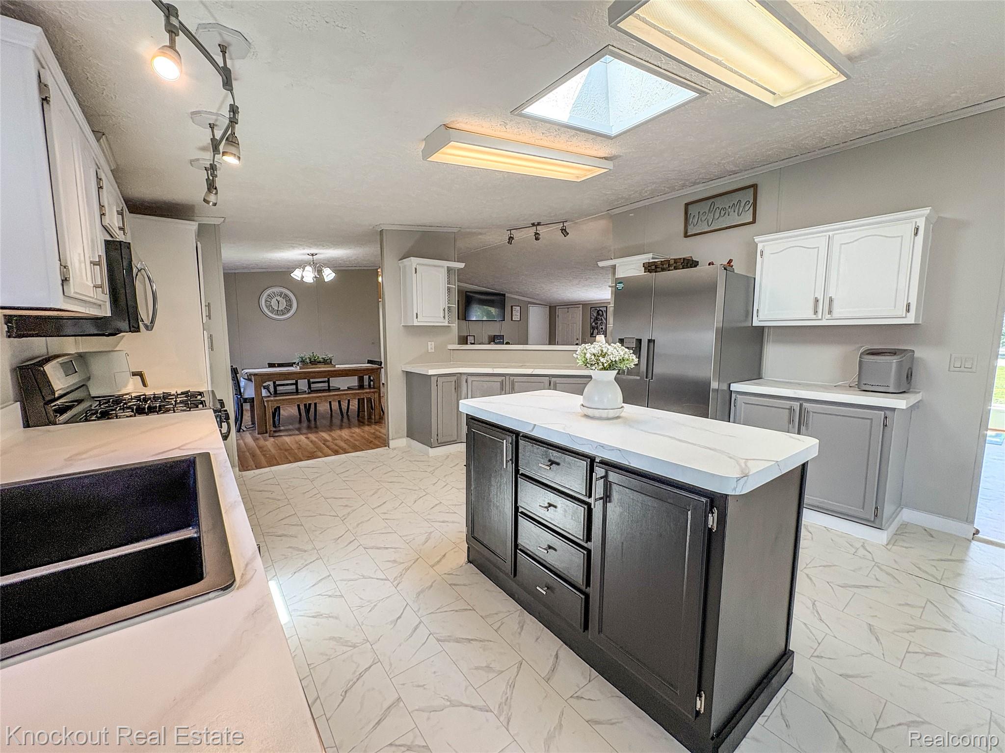7760 Bell Road Birch Run, MI 48415 - Photo 17 of 68 Kitchen featuring an island with white countertop, white and gray cabinetry, a gas range, and stainless steel refrigerator