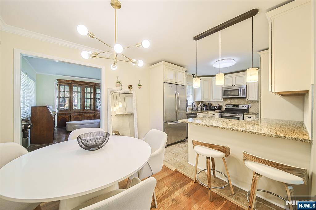 181 Crescent Street Closter, NJ 07624 - Photo 13 of 25 a kitchen with stainless steel appliances granite countertop a stove a sink a refrigerator dining table and chairs with wooden floor