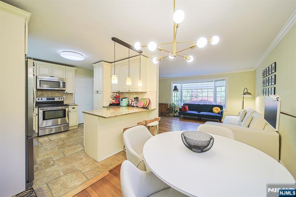 181 Crescent Street Closter, NJ 07624 - Photo 17 of 25 a kitchen with stainless steel appliances kitchen island granite countertop a sink a refrigerator a stove a dining table and chairs with wooden floor