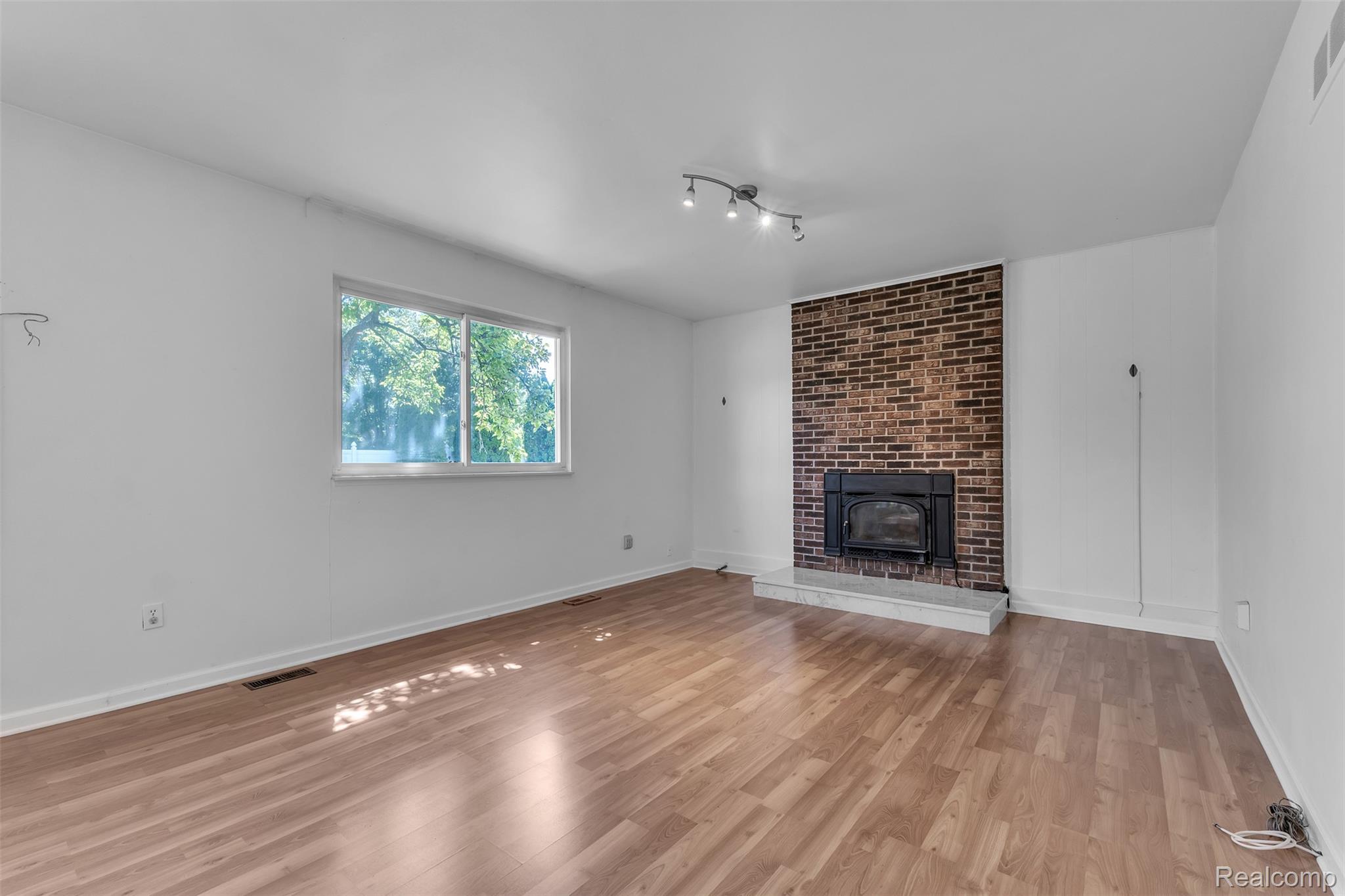 7000 Woonsocket Street Canton, MI 48187 - Photo 28 of 65 Living area featuring wood-finish flooring, a brick accent wall with a fireplace insert, and a wide window