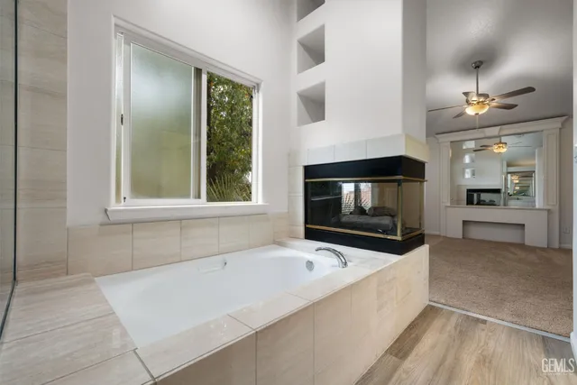 a living room with stainless steel appliances furniture a fireplace and a large window