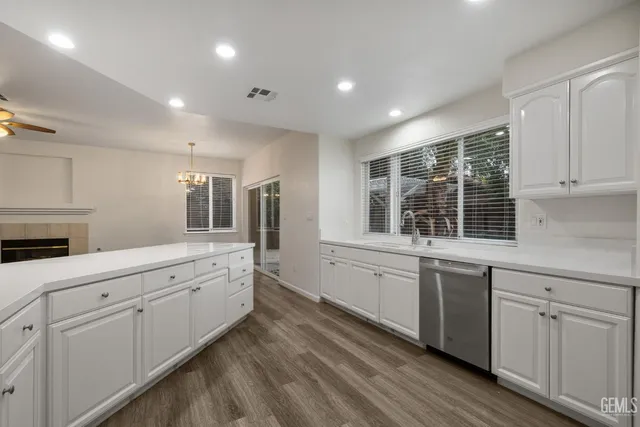 a large white kitchen with granite countertop white cabinets and stainless steel appliances