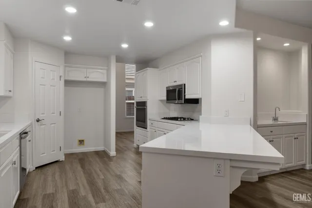 a kitchen with a sink a refrigerator and a stove top oven with wooden floor