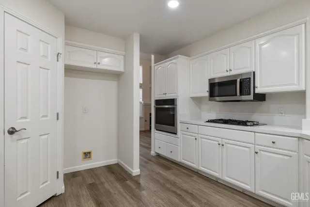 a kitchen with granite countertop white cabinets and stainless steel appliances