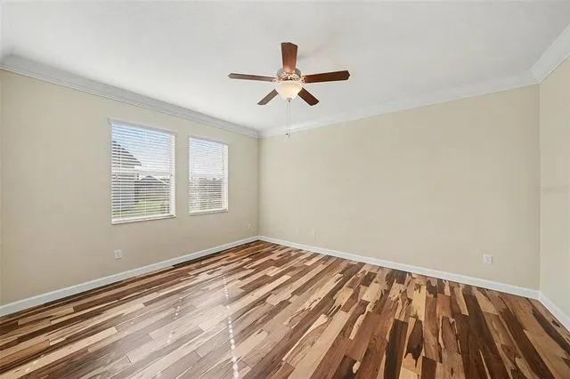 a view of empty room with wooden floor and fan